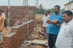डस्ट से बनी स्कूल भवन की दीवार को तोड़ते कर्मी